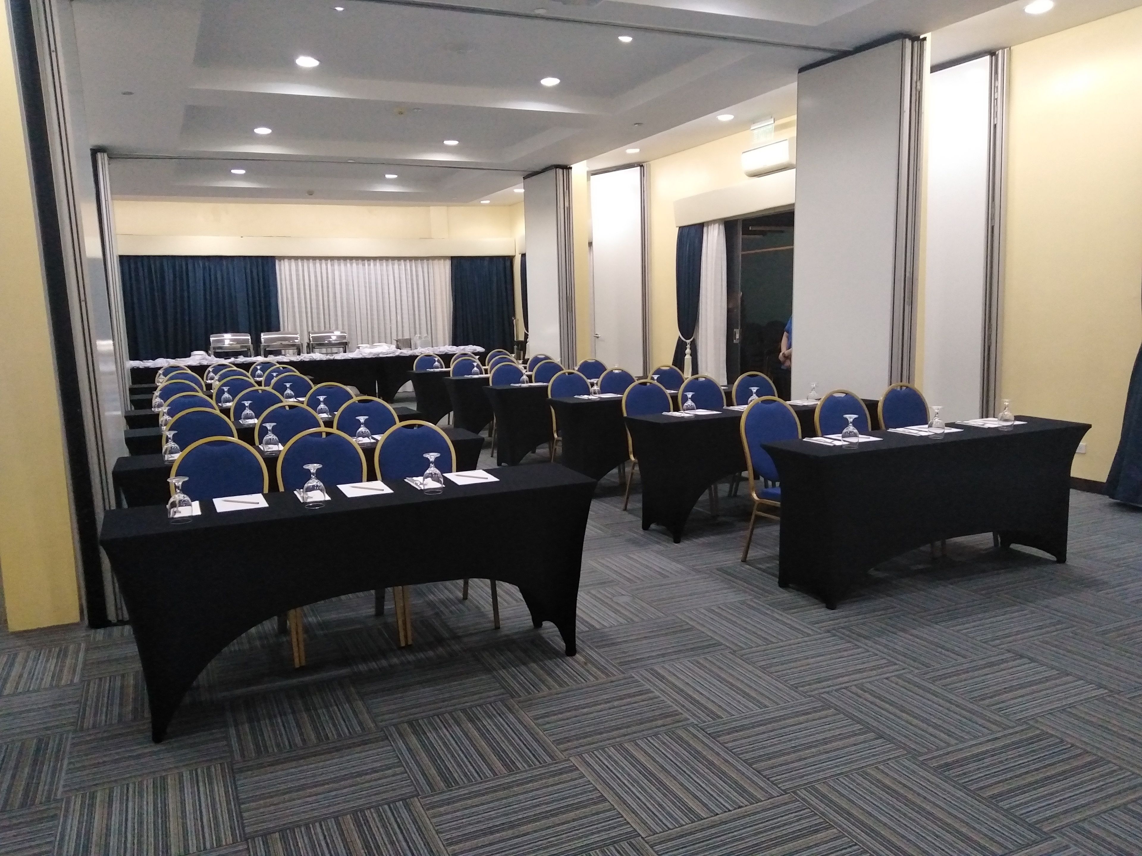 A conference room with rows of tables and chairs, equipped with nameplates and water glasses.