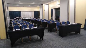 A conference room with rows of tables and chairs, equipped with nameplates and water glasses.