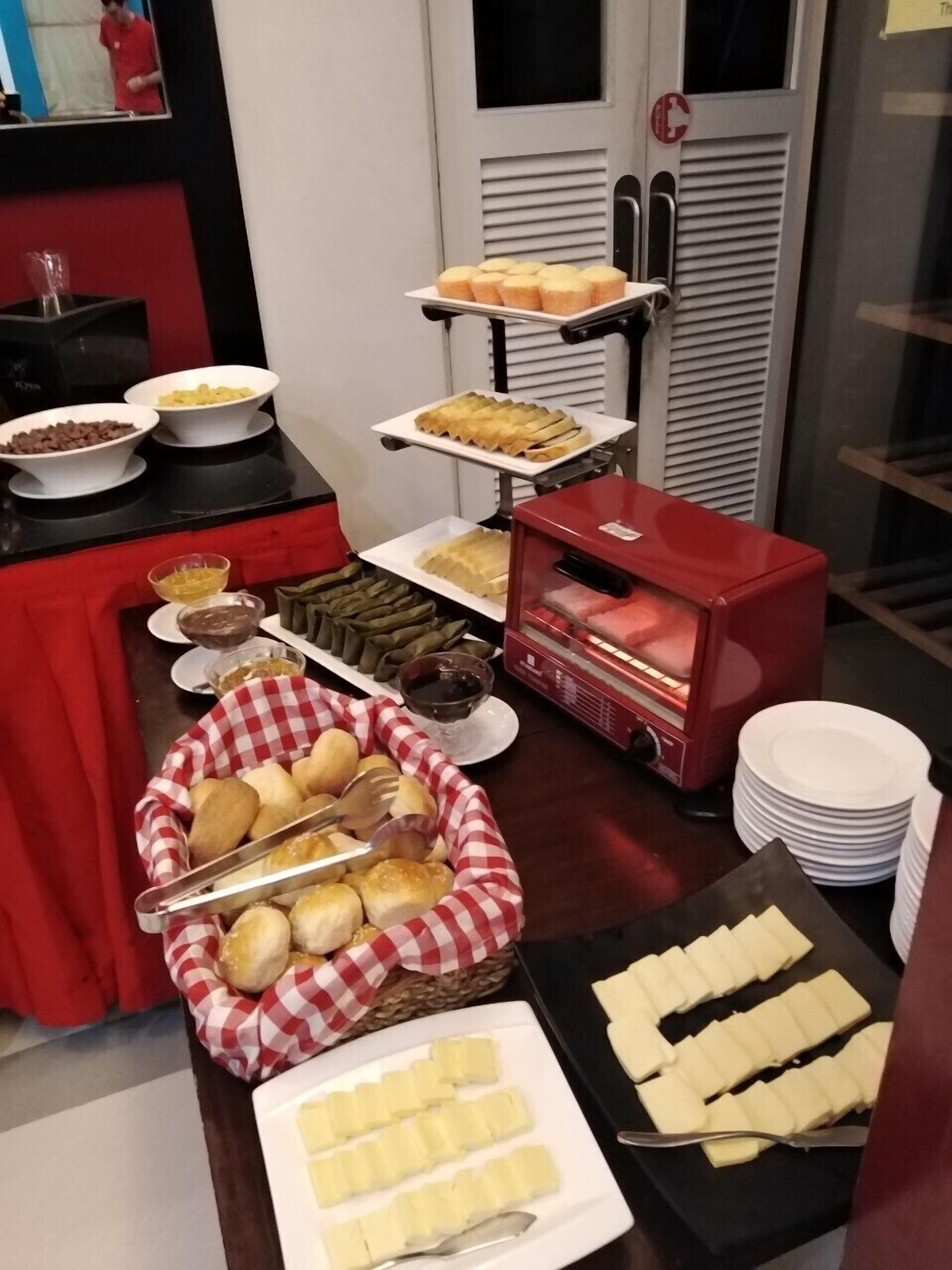 A buffet setup with various food items including bread, pastries, and condiments.