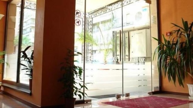 L’entrée d’un hôtel, avec une porte en verre, une horloge et un tapis rouge menant à l’entrée.