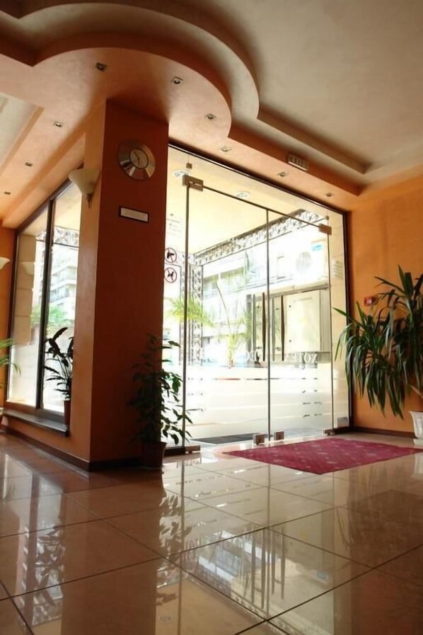 L’entrée d’un hôtel, avec une porte en verre, une horloge et un tapis rouge menant à l’entrée.