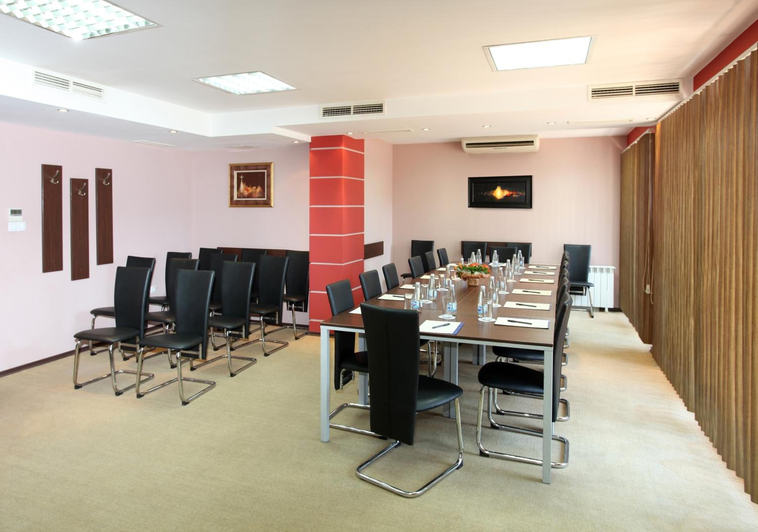 A conference room with a long table, chairs, and a red accent wall.