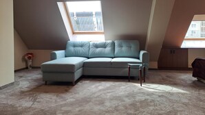 Een kamer met een lichtblauwe modulaire bank, een glazen bijzettafeltje en een dakraam.