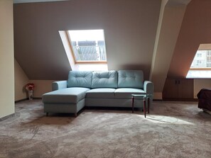 A room with a light blue sectional sofa, a small glass table, and a skylight.
