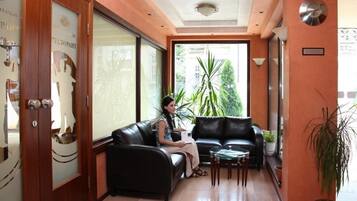 A reception area with a black leather sofa, a glass coffee table, and a potted plant.