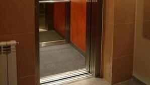 Un ascenseur doté d’un écran numérique, de panneaux en bois et d’un intérieur métallique.