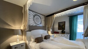 A bedroom with a large bed, a bedside table, a dresser, a decorative wall piece, and a window with curtains. - Apartment Fernerkogel (Gries im Sellrain)