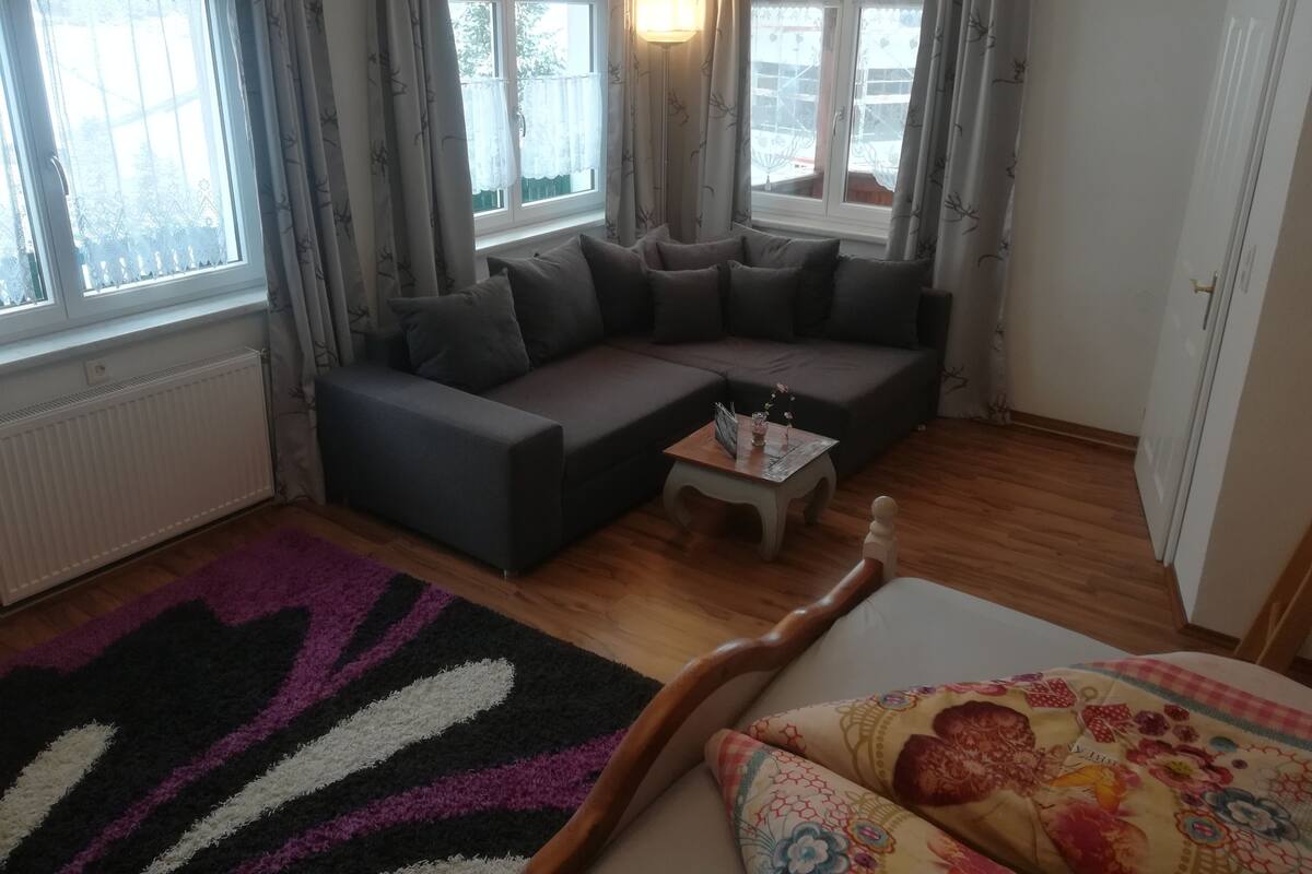Una sala de estar acogedora con un sofá modular, una mesita de centro y una alfombra estampada.