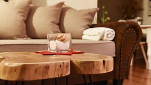 A cozy room with a wooden coffee table, a glass with a decorative item, a brown leather chair, and a bed with beige pillows. - Apartment Fernerkogel (Gries im Sellrain)
