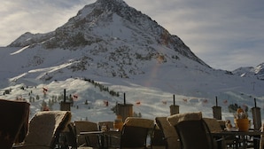 A mountain view with a restaurant seating area in the foreground. - Apartment Fernerkogel (Gries im Sellrain)
