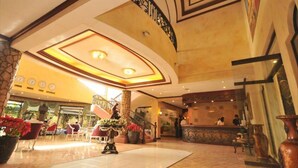 A spacious lobby with a marble floor, a central staircase, and a reception desk. - Queen Margarette Hotel - Main (Lucena)