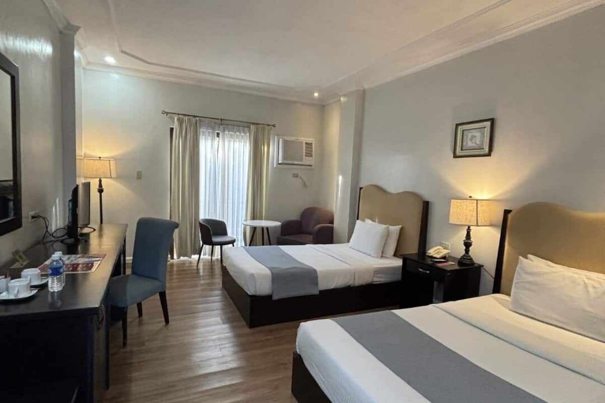 Een hotelkamer met twee bedden, een bureau met stoel, een tafeltje en een televisie.