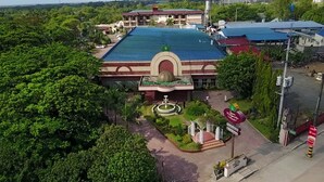 A hotel with a large swimming pool, surrounded by lush greenery. - Queen Margarette Hotel - Main (Lucena)