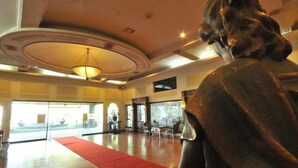 A spacious lobby with a red carpet, a large chandelier, and a statue. - Queen Margarette Hotel - Main (Lucena)