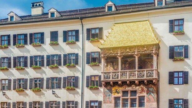 Um edifício com várias janelas, algumas com persianas, e um telhado dourado característico.