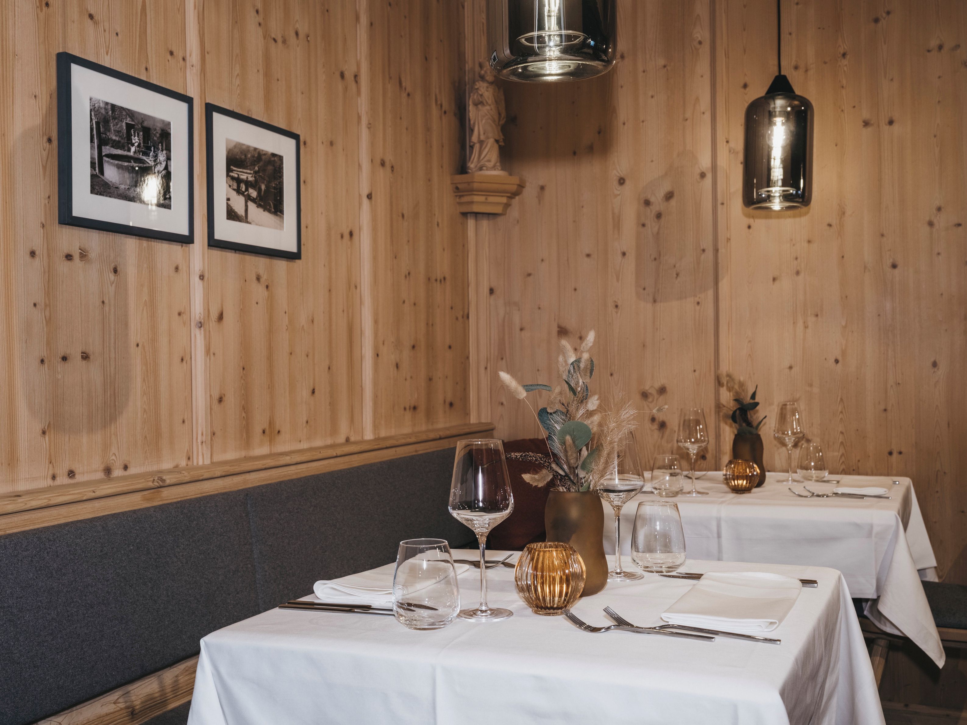 Een restaurantinterieur met houten wanden, ingelijste foto's en gedekte tafels.