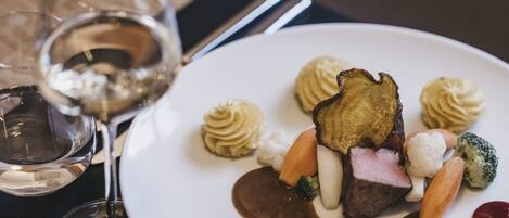 Ein weißer Teller mit verschiedenen Speisen, darunter Fleisch, Gemüse und Soße.