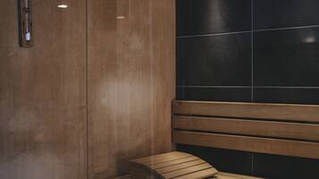A wooden bench with a cushion in a room with wooden walls and a black tiled wall.