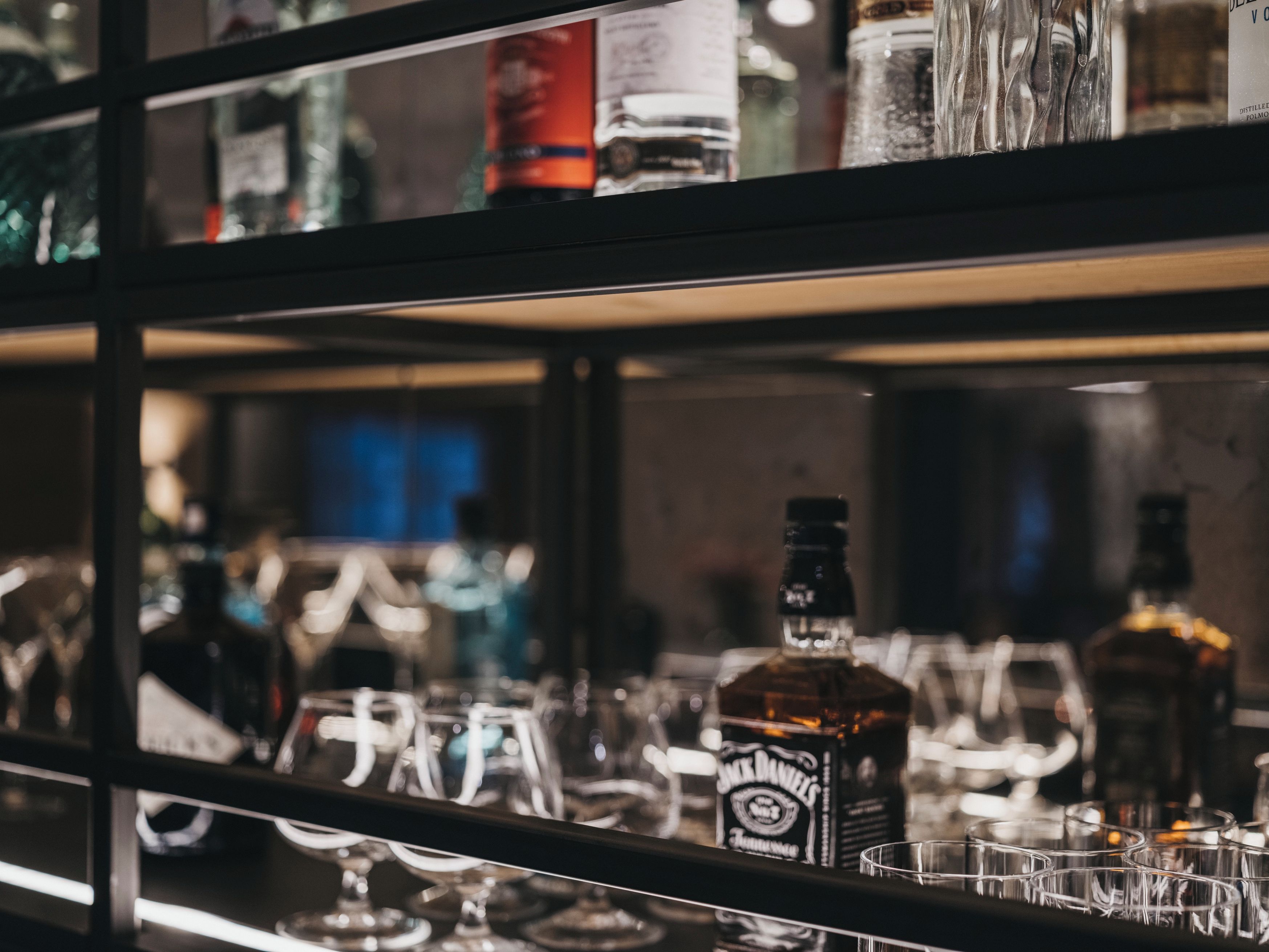 A bar area with shelves containing various bottles and glasses.