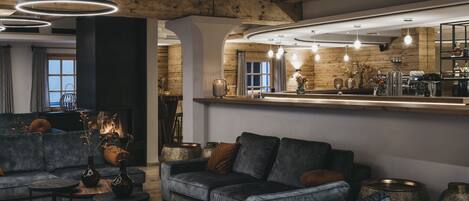 A modern living room with a fireplace, dark leather sofas, and a wooden ceiling.