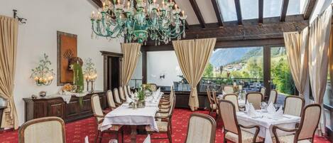 Uma sala de jantar com várias mesas, cadeiras e um candelabro.