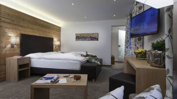 Une chambre d’hôtel moderne, dotée d’un grand lit, d’un bureau, d’un canapé, d’une télévision et d’un tableau au mur.