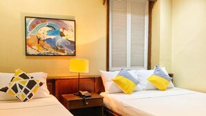 Habitació d'hotel amb dos llits, una taula de nit, una làmpada, un quadre a la paret i una finestra amb persianes.