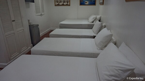 A room with two single beds, a wardrobe, and a small table with a lamp.
