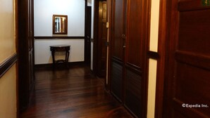 Passadís estret amb terres de fusta, portes, una taula petita i un mirall al mur.