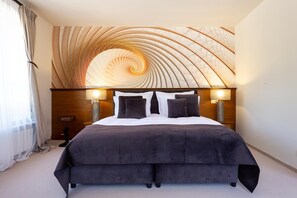 A hotel room with a large bed, two bedside lamps, and a unique ceiling design. - Sokol (Samokov)