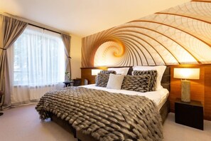 A modern hotel room with a large bed, a curved ceiling design, and a view of the outdoors through the window. - Sokol (Samokov)