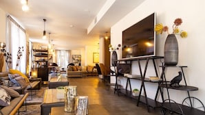 A modern living room with a large flat-screen TV, a bookshelf, and a decorative bird sculpture.