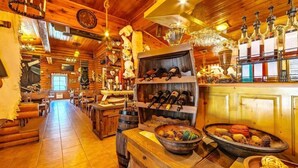 Un interior rústico de madera con un amplio comedor, mesas de madera y una zona de bar con botellas y vasos.