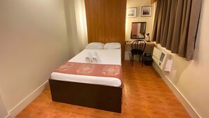 A small, neatly arranged bedroom with a bed, a desk, and a chair. - Stonehouse Bed and Breakfast (Quezon City)