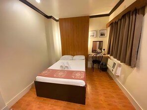 A small, neatly arranged bedroom with a bed, a desk, and a chair. - Stonehouse Bed and Breakfast (Quezon City)