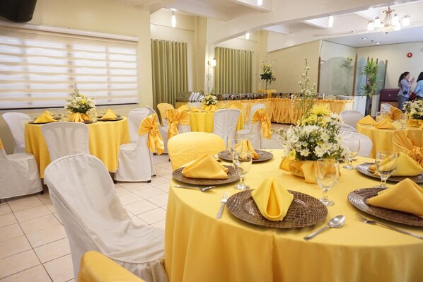 A banquet hall with round tables covered in yellow tablecloths and white chairs, each adorned with yellow sashes. - Stonehouse Bed and Breakfast (Quezon City)