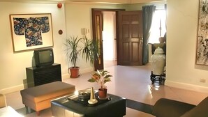 A living room with a sofa, a coffee table, a television, and a potted plant. - Stonehouse Bed and Breakfast (Quezon City)