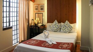 A hotel room with a bed, a desk, and a chair. There are two pillows on the bed. - Stonehouse Bed and Breakfast (Quezon City)