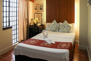 A hotel room with a bed, a desk, and a chair. There are two pillows on the bed. - Stonehouse Bed and Breakfast (Quezon City)