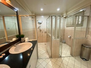 A modern bathroom with a glass-enclosed shower, a large mirror, and a black countertop with a sink. - Stonehouse Bed and Breakfast (Quezon City)