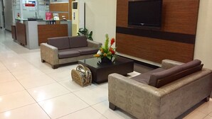 A hotel lobby with a reception desk, sofas, a coffee table, and a television. - The Studio 87 Residences (Quezon City)