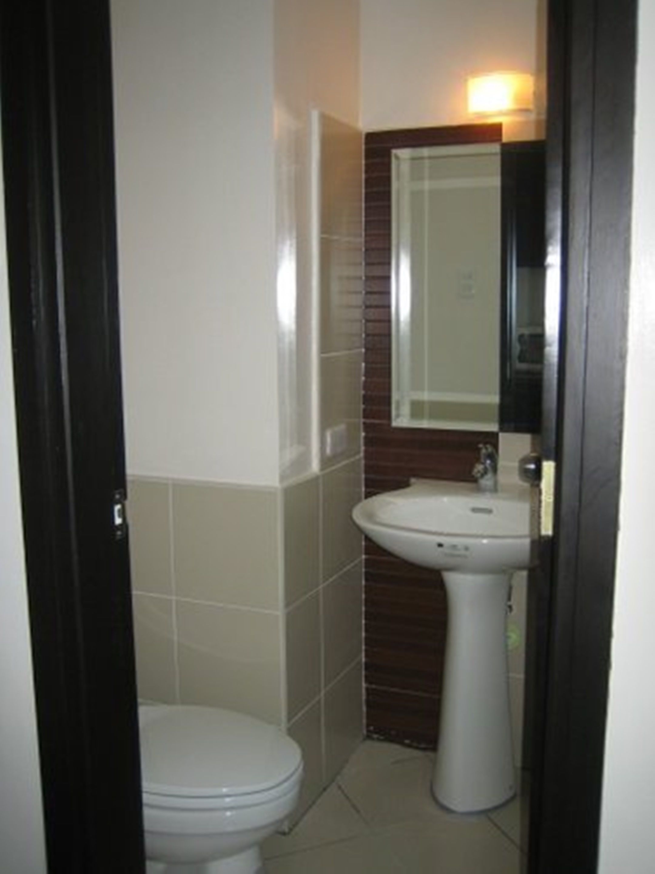 A small bathroom with a toilet, a sink, and a mirror.