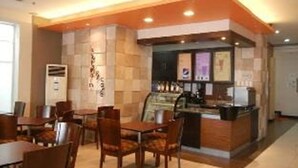 A hotel lobby with a central bar area, seating arrangements, and a reception desk. - The Studio 87 Residences (Quezon City)