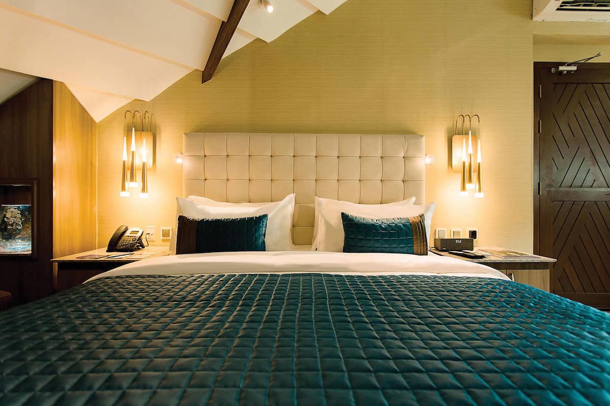A hotel room with a large bed, two bedside tables, a telephone, and wall-mounted lighting.
