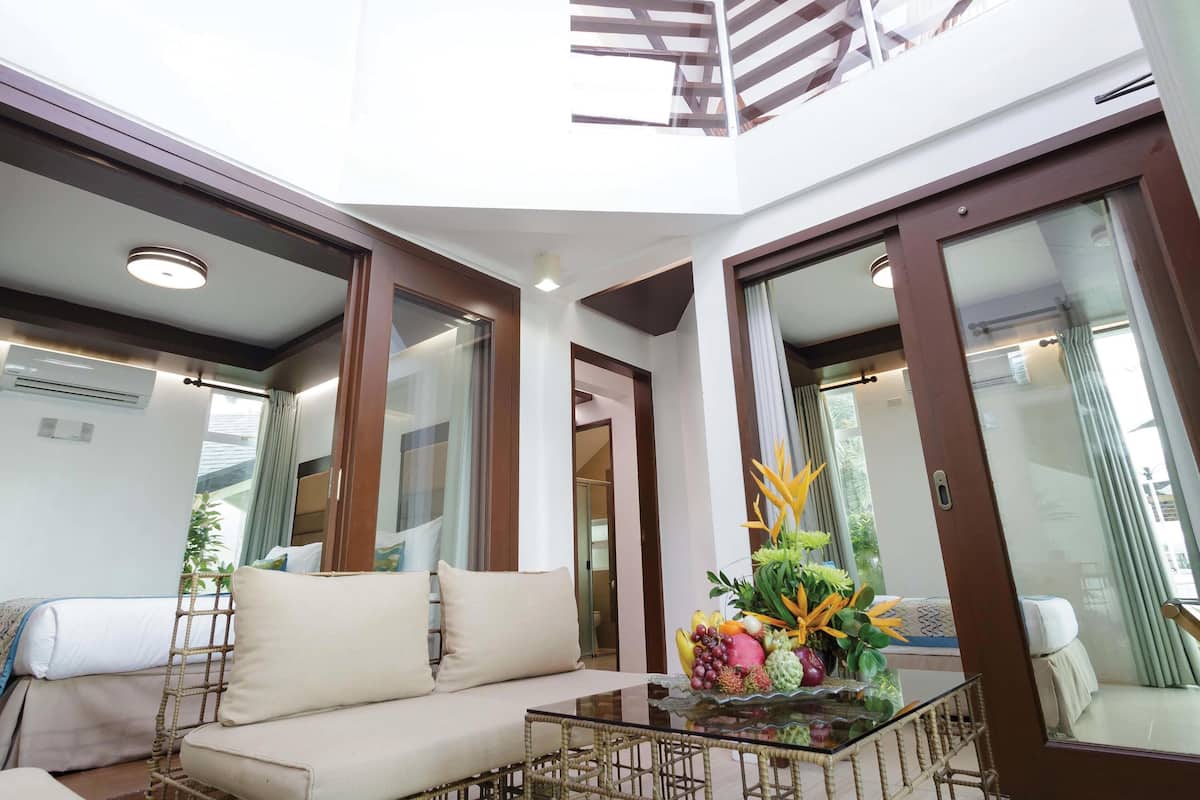 A modern living room with a sofa, a glass coffee table, and a balcony with a railing.