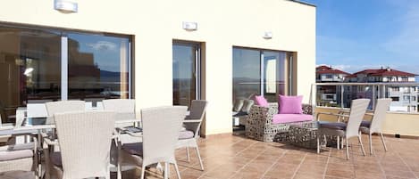 Una terraza con mobiliario exterior, ventanas amplias y vistas a la ciudad.