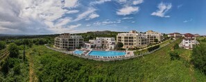 A resort with multiple buildings, a swimming pool, and a lush green landscape.