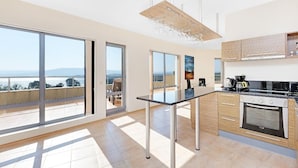 A modern kitchen with large windows, a dining area, and a view of the sea. - Byala Panorama Resort (Byala)