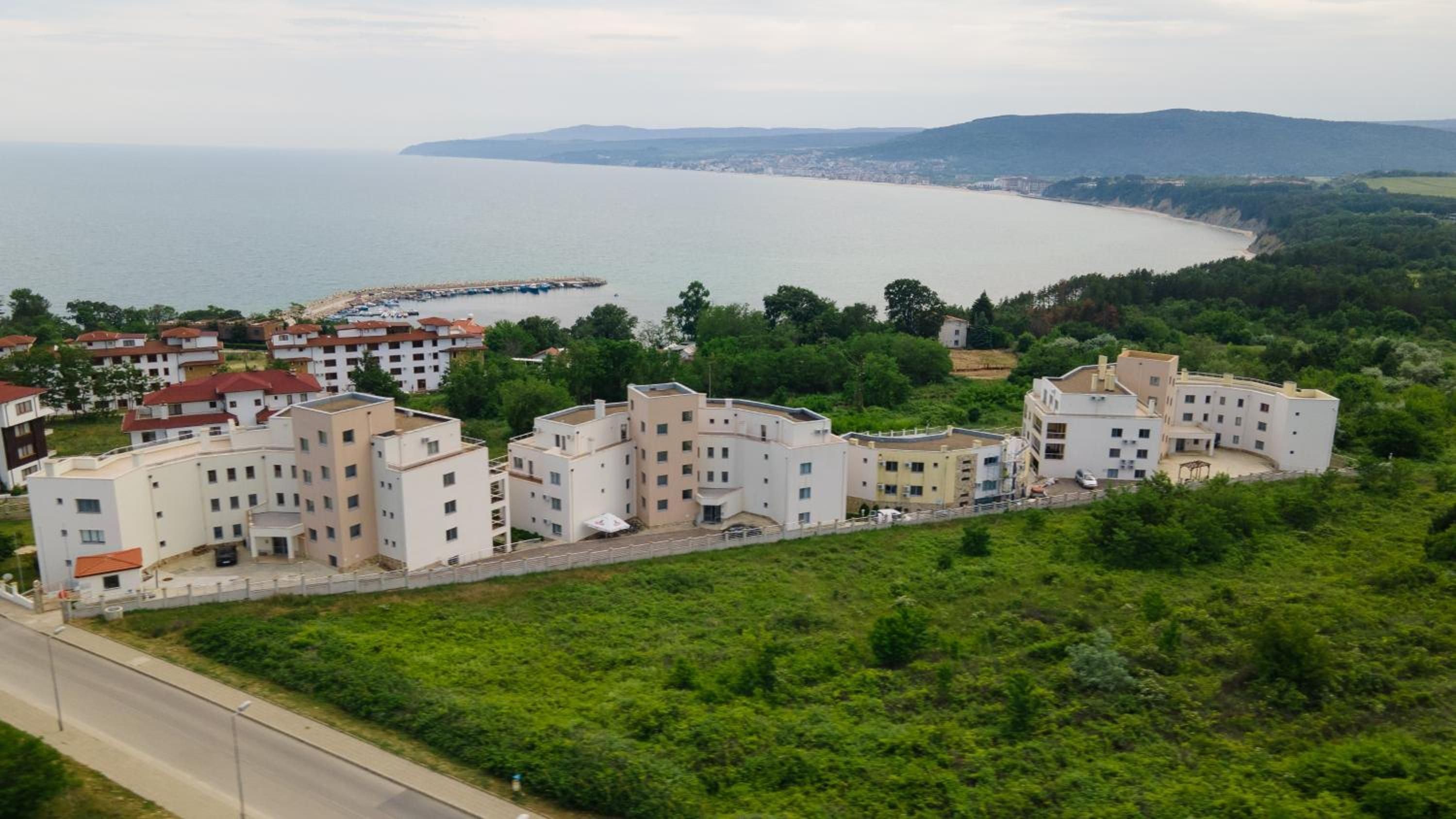 Área residencial com edifícios altos, uma estrada e a costa ao fundo.