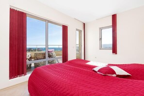 A hotel room with a large bed, a balcony with a view, and a window with curtains.